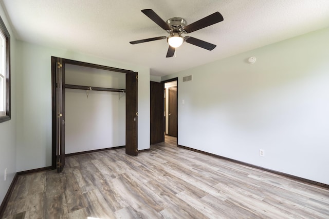 unfurnished bedroom featuring light wood finished floors, a closet, baseboards, and a ceiling fan
