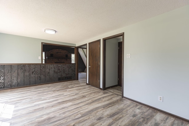 unfurnished living room with wood finished floors, a fireplace, a textured ceiling, and baseboards