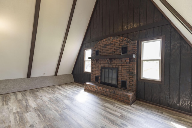 unfurnished living room with wood finished floors, a brick fireplace, and wooden walls