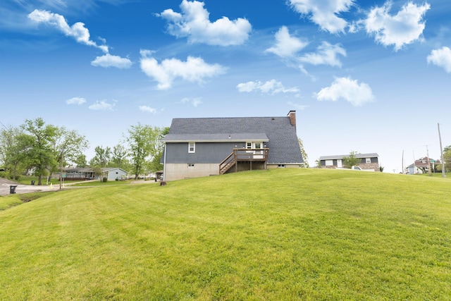 rear view of property featuring stairs, a lawn, a chimney, and a deck