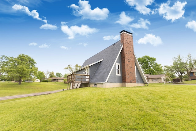 back of house with a lawn, a shingled roof, a deck, and a chimney