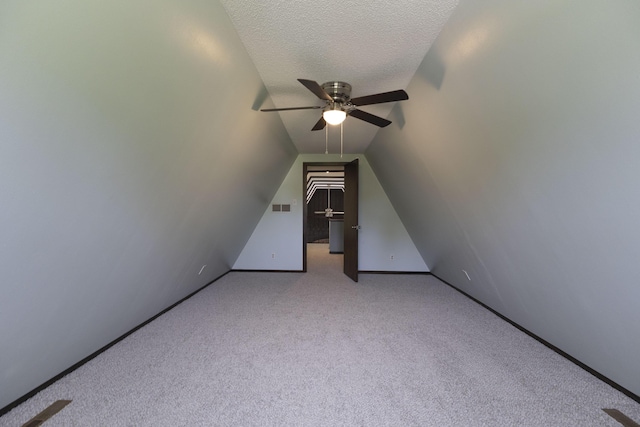 bonus room featuring a ceiling fan, carpet, baseboards, lofted ceiling, and a textured ceiling