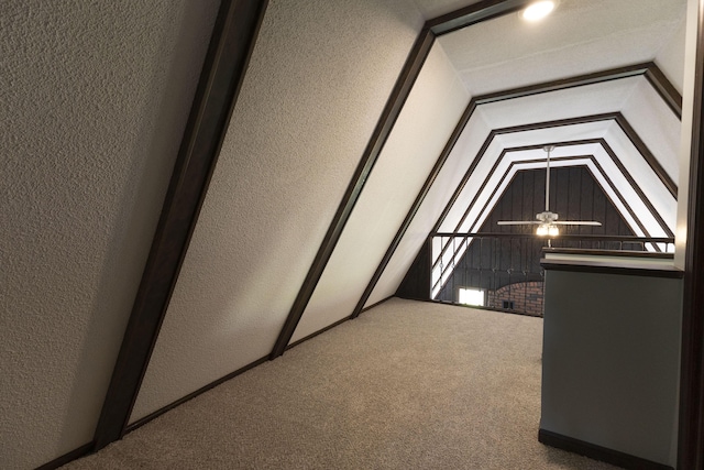 additional living space featuring a textured wall, carpet floors, and lofted ceiling