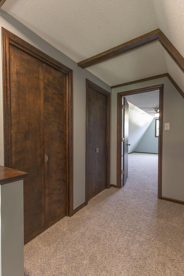 hallway with light colored carpet and a textured ceiling