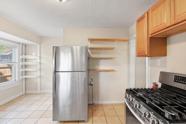 kitchen featuring stainless steel appliances, light tile patterned flooring, and baseboards