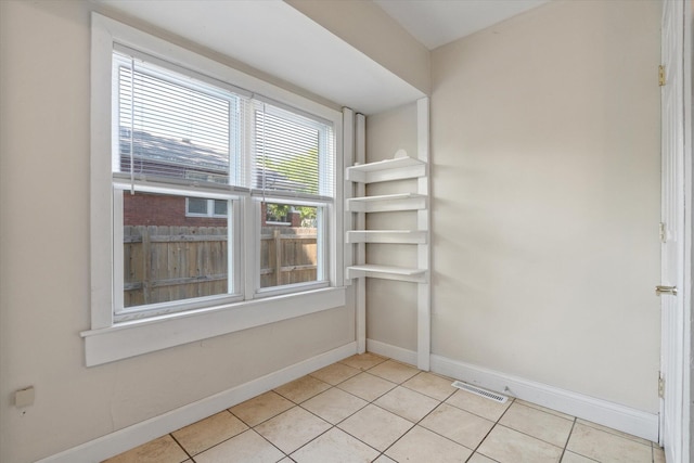 spare room with light tile patterned flooring and baseboards