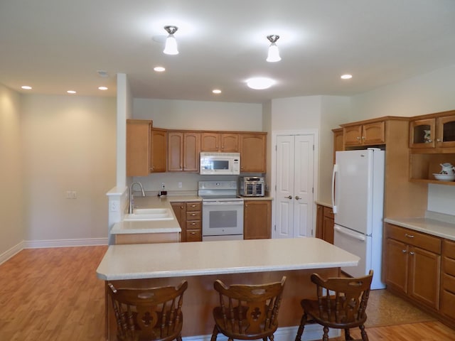320 S Jefferson St, Centralia, MO 65240 - kitchen with white appliances, a sink, a peninsula, a breakfast bar, and light countertops