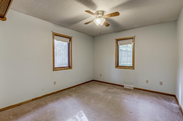 empty room with carpet, a ceiling fan, baseboards, and a textured ceiling