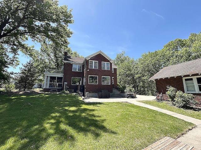 view of front of property with brick siding, a front yard, a chimney, and a patio area