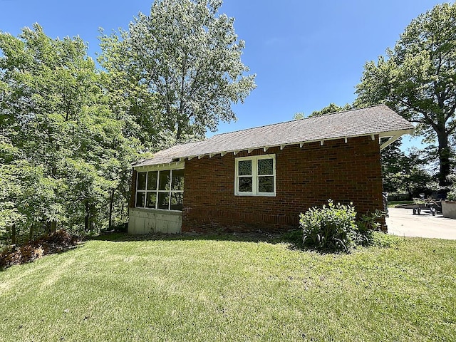 view of home's exterior featuring a sunroom, a yard, and brick siding