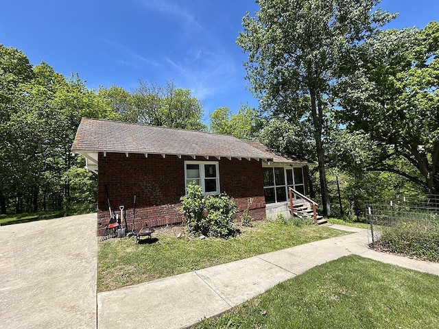 ranch-style house with a front lawn, a sunroom, brick siding, and a shingled roof