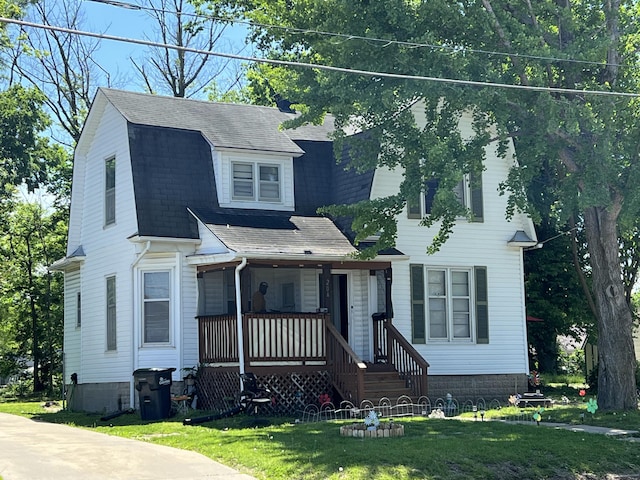 dutch colonial with a porch, a front lawn, and roof with shingles