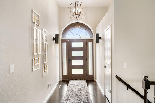 foyer entrance with a chandelier, dark wood-type flooring, and baseboards