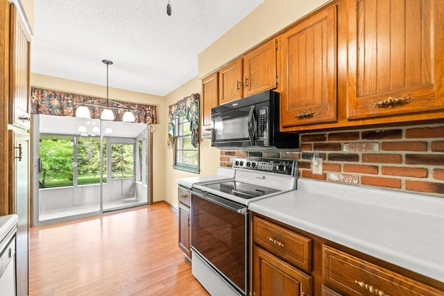 4 Halley Ct, Fulton, MO 65251 - kitchen with range with electric cooktop, black microwave, brown cabinetry, light countertops, and light wood-style floors