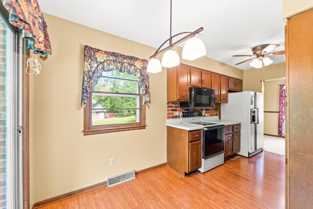 4 Halley Ct, Fulton, MO 65251 - kitchen with range with electric cooktop, black microwave, light wood finished floors, light countertops, and brown cabinets