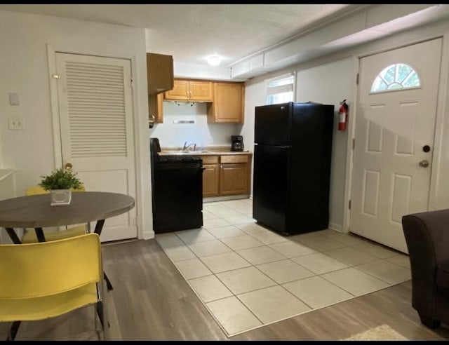 kitchen with freestanding refrigerator, stove, light wood-style flooring, and a sink