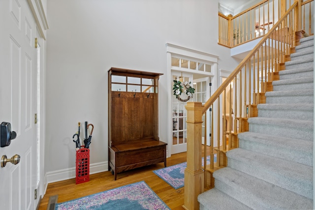 foyer entrance with wood finished floors, stairway, a high ceiling, and baseboards
