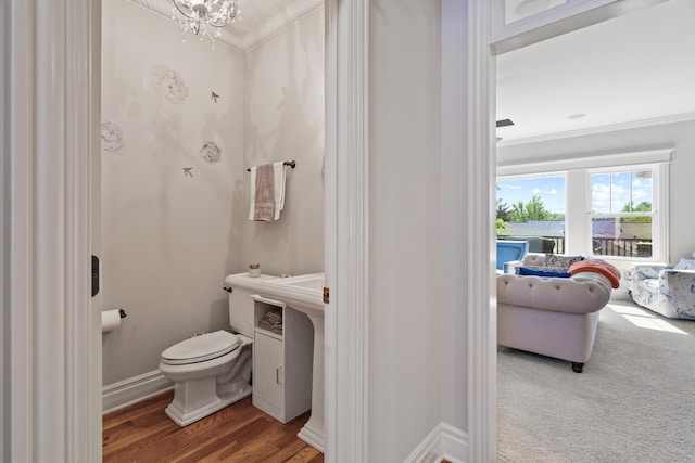 bathroom with toilet, wood finished floors, a chandelier, ornamental molding, and baseboards