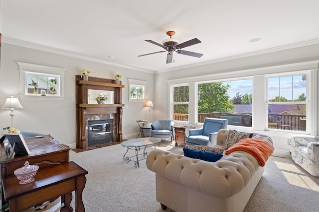 carpeted living area with a premium fireplace, a ceiling fan, crown molding, and baseboards