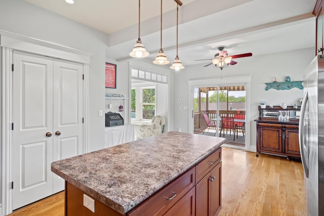 kitchen featuring freestanding refrigerator, ceiling fan, light wood finished floors, pendant lighting, and a kitchen island