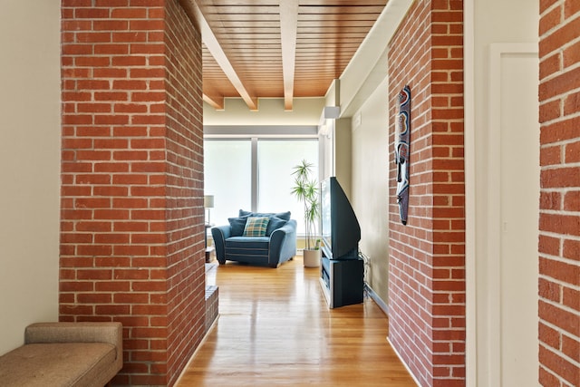 hallway with light wood finished floors, brick wall, wood ceiling, and beamed ceiling
