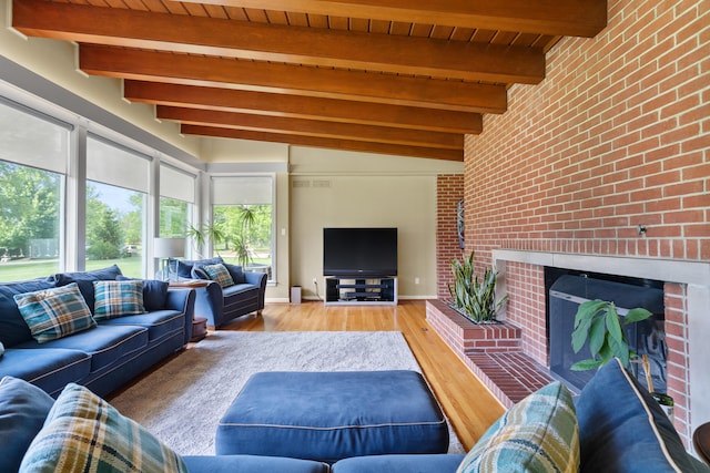 living area featuring light wood-style floors, beam ceiling, a brick fireplace, brick wall, and wooden ceiling