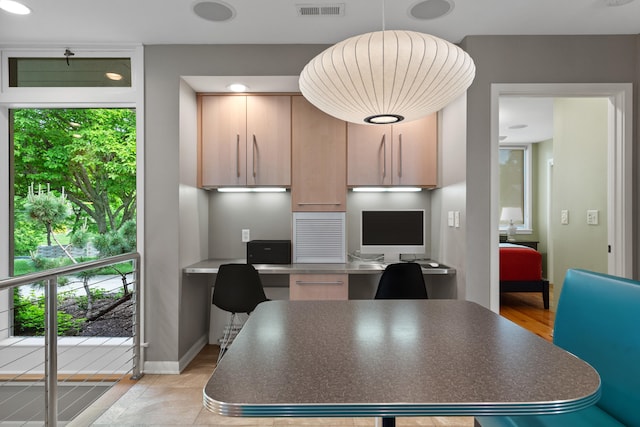 kitchen with light wood-style floors, dark countertops, light brown cabinetry, baseboards, and a center island