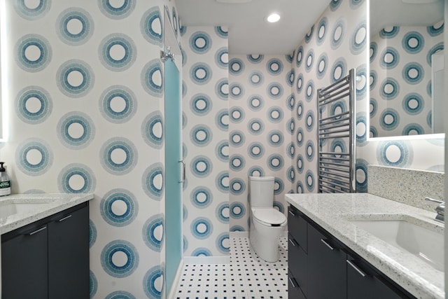 bathroom with two vanities, toilet, a shower, and a towel warmer