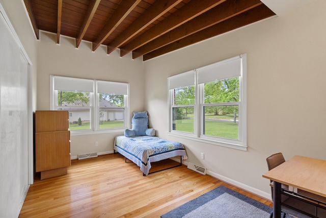 bedroom featuring beamed ceiling, multiple windows, light wood-style floors, wooden ceiling, and baseboards