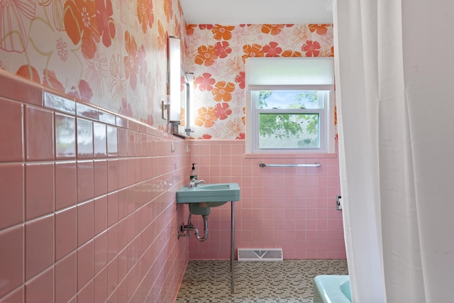 full bathroom with wallpapered walls, wainscoting, tile walls, a shower with curtain, and a bath