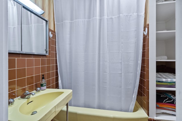 bathroom featuring a sink, tile walls, and shower / bath combo