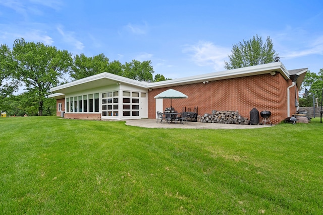 rear view of property with brick siding, a patio area, and a yard