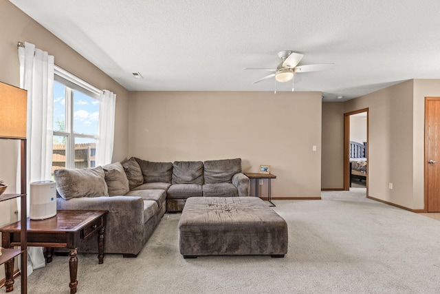 living area featuring ceiling fan, carpet flooring, baseboards, and a textured ceiling