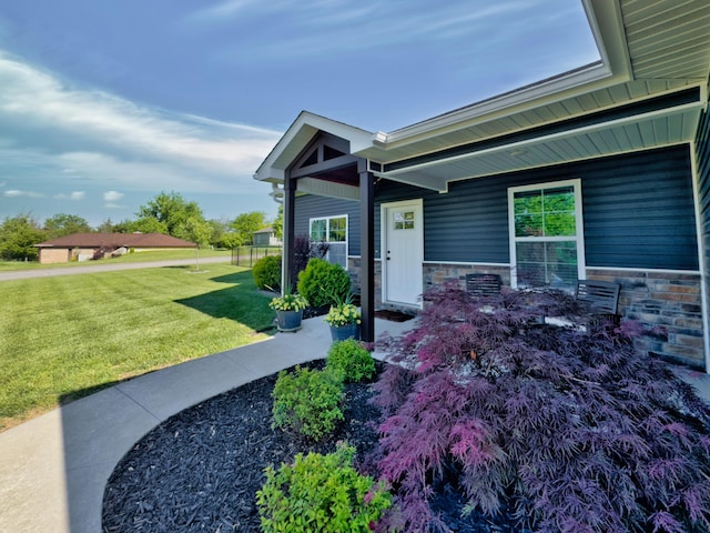 property entrance with a yard, stone siding, and covered porch