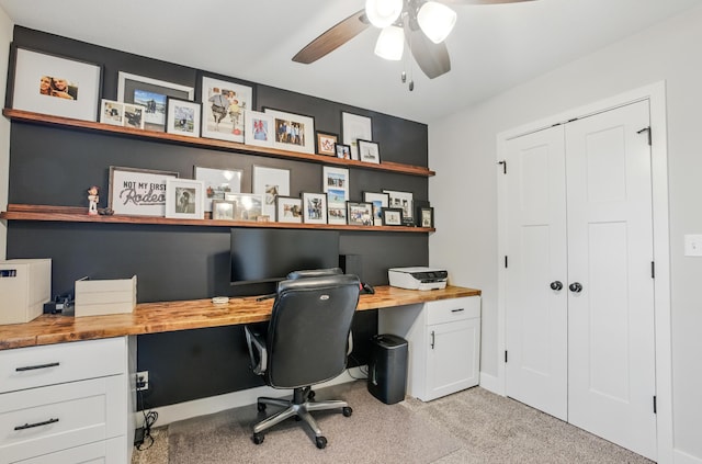 office area featuring built in desk, light carpet, and ceiling fan