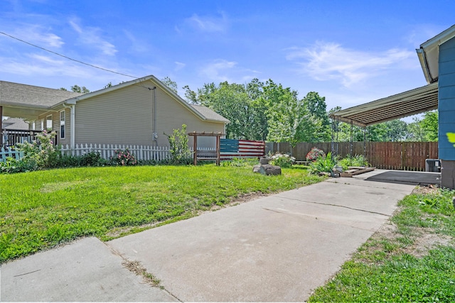 view of yard featuring fence and concrete driveway