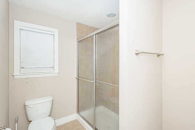 bathroom featuring a shower stall, toilet, tile patterned floors, and baseboards