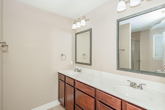 bathroom with an enclosed shower, double vanity, tile patterned flooring, and baseboards