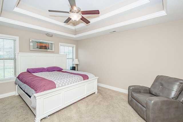 bedroom featuring a tray ceiling, light carpet, ornamental molding, baseboards, and a ceiling fan