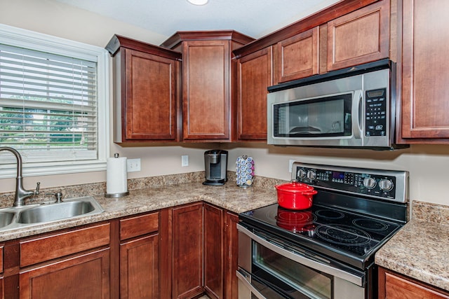 kitchen featuring appliances with stainless steel finishes, a sink, and light countertops