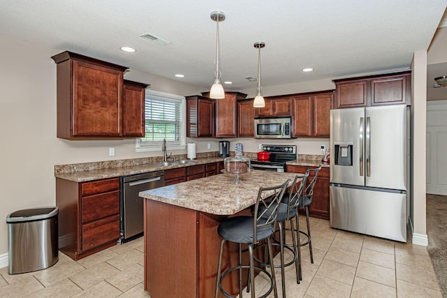 kitchen featuring stainless steel appliances, a sink, a breakfast bar area, a center island, and baseboards