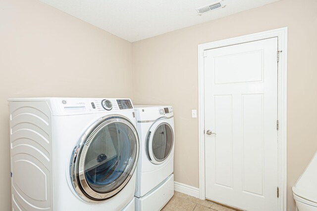 clothes washing area featuring independent washer and dryer, baseboards, and light tile patterned floors