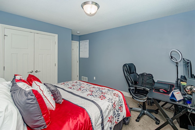 carpeted bedroom with a closet and a desk