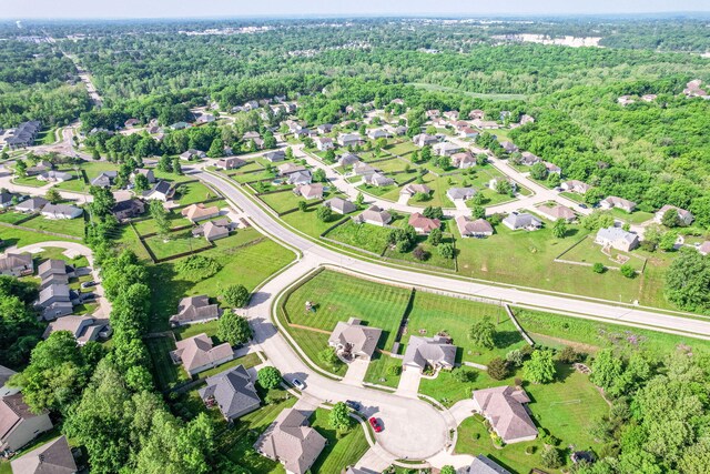 aerial view of property's location featuring a forest and nearby suburban area