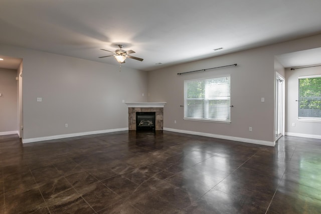 unfurnished living room with ceiling fan, a tile fireplace, baseboards, and dark tile patterned flooring