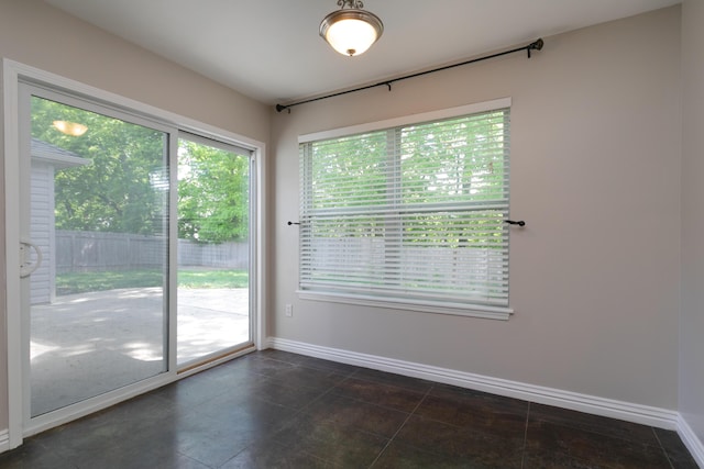unfurnished room featuring baseboards and dark tile patterned flooring