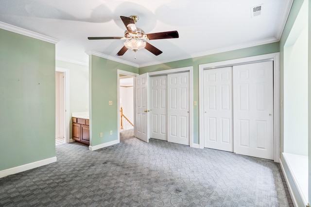 unfurnished bedroom with dark carpet, two closets, ornamental molding, baseboards, and a ceiling fan