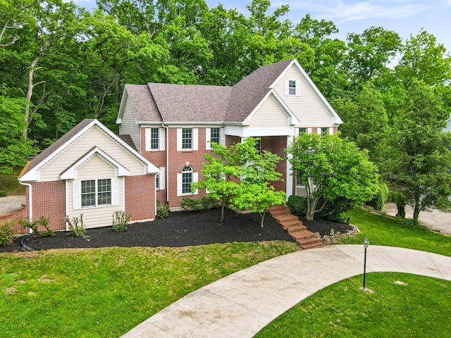 view of front of property featuring brick siding, a front yard, and a shingled roof