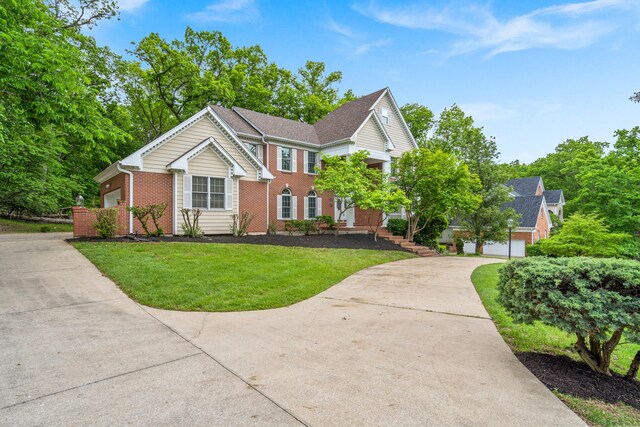 view of front facade featuring concrete driveway, brick siding, and a front yard