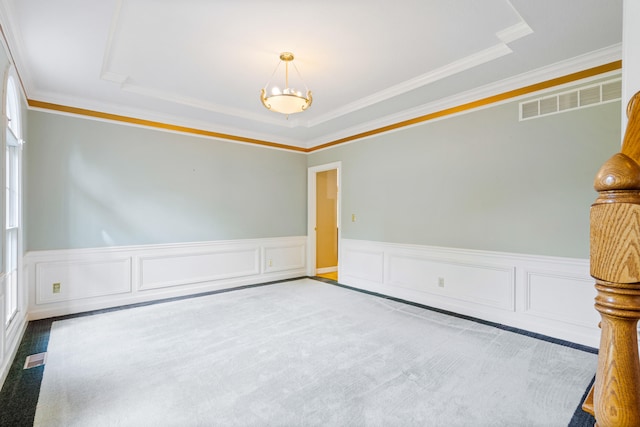 carpeted spare room featuring wainscoting, crown molding, a tray ceiling, and a chandelier